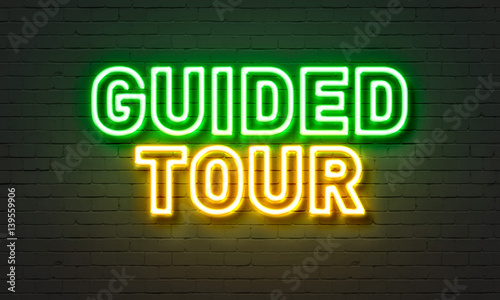 Guided tour neon sign on brick wall background. photo