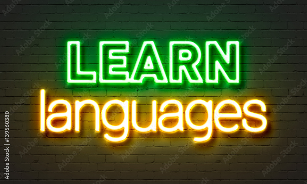 Learn languages neon sign on brick wall background.