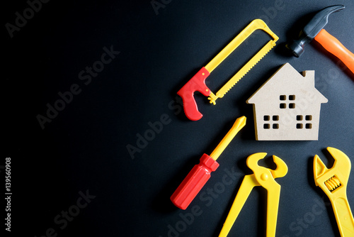 Wooden house toy and construction tools toy on black background with copy space.Home Repair concept, Repair maintenance concept, Renovation concept © bubbers