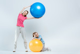 mother and daughter exercising with fitness balls on white