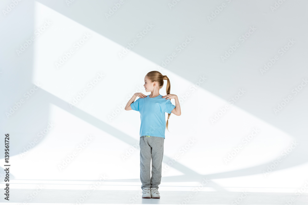 Full length view of happy little girl in sportswear exercising Full length view of happy little girl in sportswear exercising