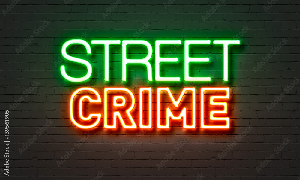 Street crime neon sign on brick wall background.