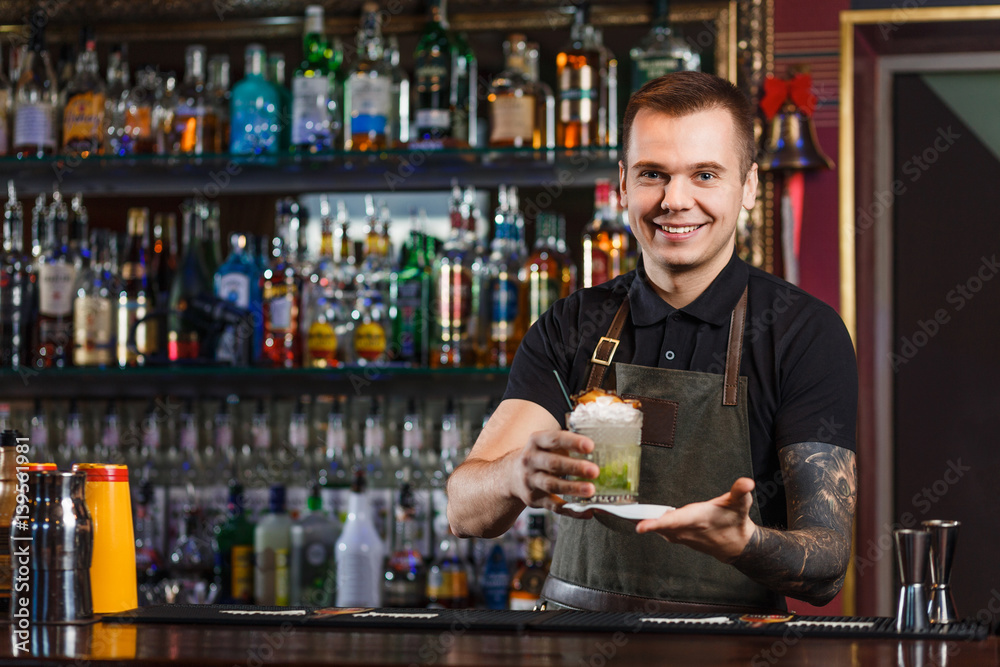 Cheerful bartender gives the cocktail to customer.