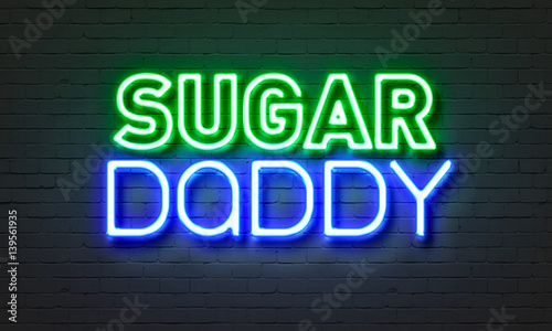 Sugar daddy neon sign on brick wall background.