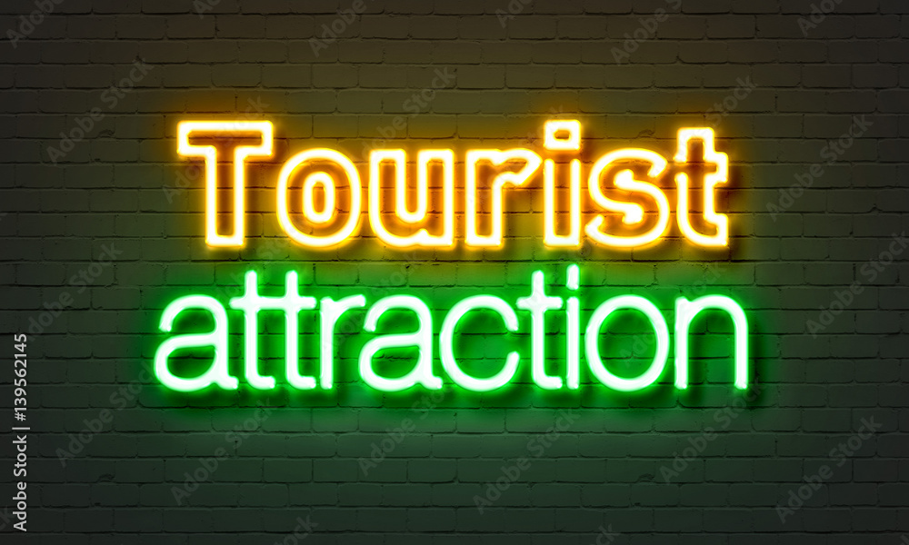 Tourist attraction neon sign on brick wall background.