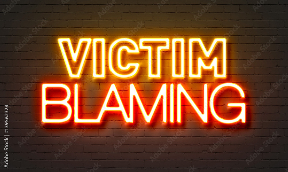 Victim blaming neon sign on brick wall background. Victim blaming neon sign on brick wall background.