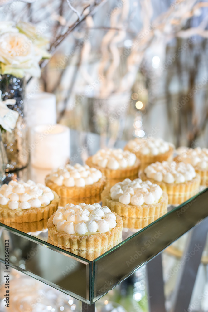 Cupcakes with white cream on the table decorated with white flowers and candles