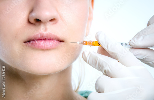 The doctor makes an injection into the lips of a young patient.