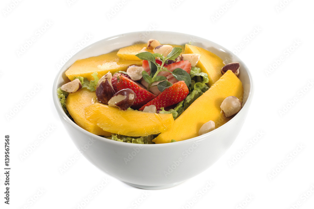 A healthy fresh salad of green lettuce with nuts, mango, strawberry, tomatoes in a white bowl isolated over white background. A healthy fresh salad of green lettuce with nuts, mango, strawberry, tomatoes in a white bowl isolated over white background.