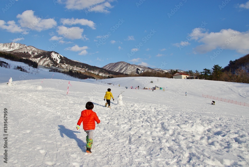 スキー場で雪だるまを作る子ども