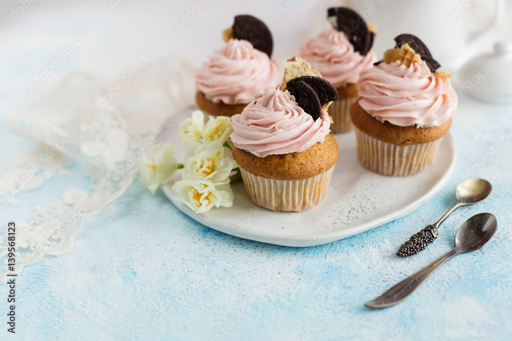 Vanilla cupcakes with chocolate chip cookies, decorated with flowers on a blue background Vanilla cupcakes with chocolate chip cookies, decorated with flowers on a blue background