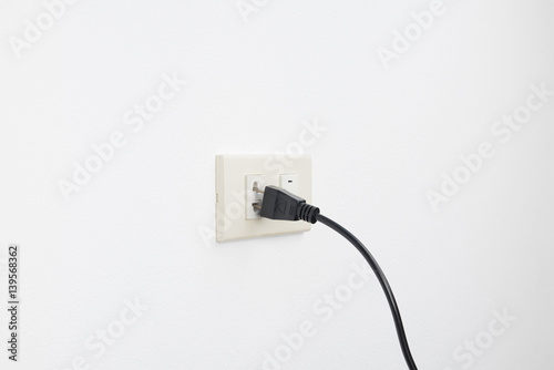 Fotografija Loose plug and falling from outlet electric shock on white wall background, chec