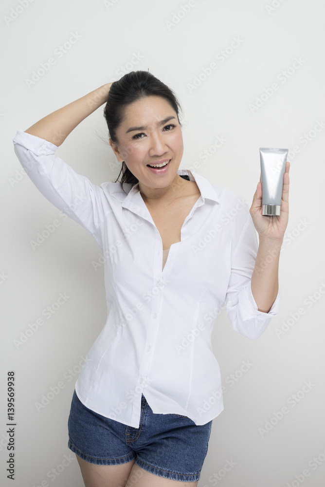 Beauty series: Asian woman holding tube of moisturizer against white background Beauty series: Asian woman holding tube of moisturizer against white background