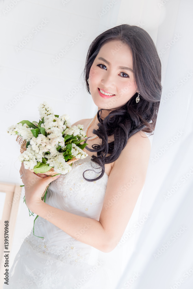 Beautiful asian bride holding flower bouquet in room Beautiful asian bride holding flower bouquet in room