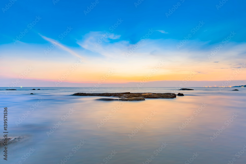 Obraz premium Long exposure shot of calmness sea and the rock in beautiful sunset sky