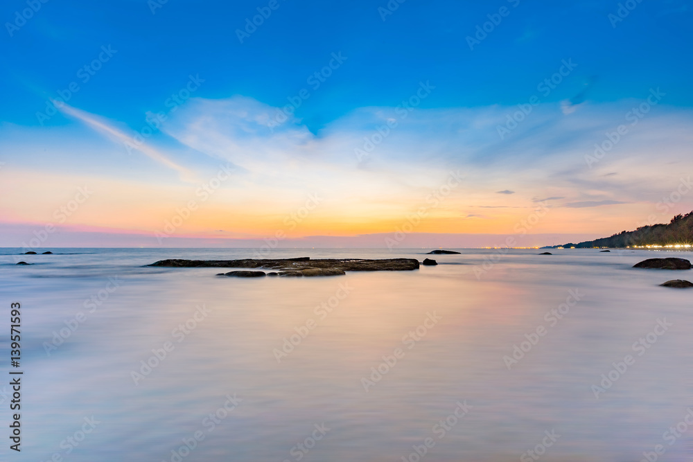 Long exposure shot of calmness sea and the rock in beautiful sunset sky