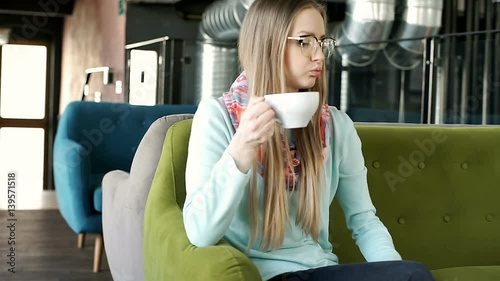 Irritated girl sitting in the cafe's loft and waiting for someone
 photo