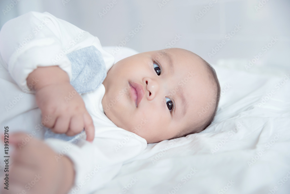 Little asian child lying on bed and looking something Little asian child lying on bed and looking something