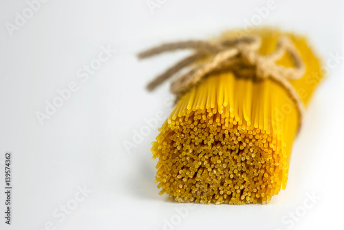 raw pasta tied with a rope on a white background