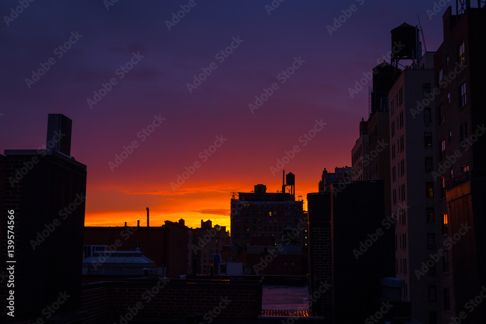 Watching the sun setting on an Upper West Side rooftop, colorful sky, water towers
