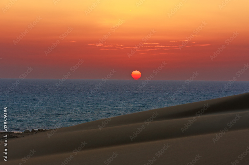 Colorful sunset on sea in background of desert