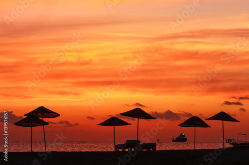 Silhouette parasol on coast on background of beautiful sunset