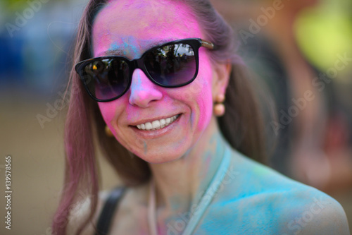 Portrait of a painted woman in sunglasses at the festival of Holi colors.