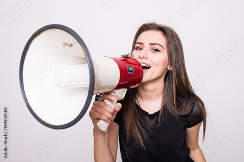 Pretty girl shouting into megaphone on copy space