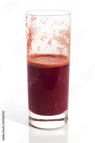 A glass of half full red healthy juice isolated over a white background
