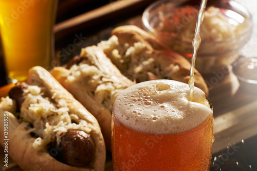 pouring beer into mug with bratwursts in background photo