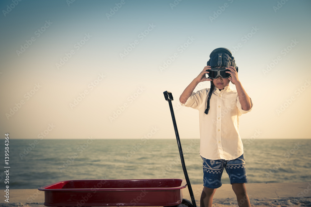 Obraz premium Boy playing aviator on beach, retro tone photo