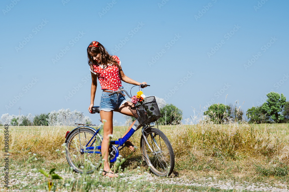 Joyful beautiful woman on a bicycle in the field landscape blue sky background outdoors Joyful beautiful woman on a bicycle in the field landscape blue sky background outdoors