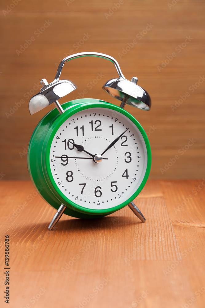 classic green alarm clock morning wake-up time on wood background