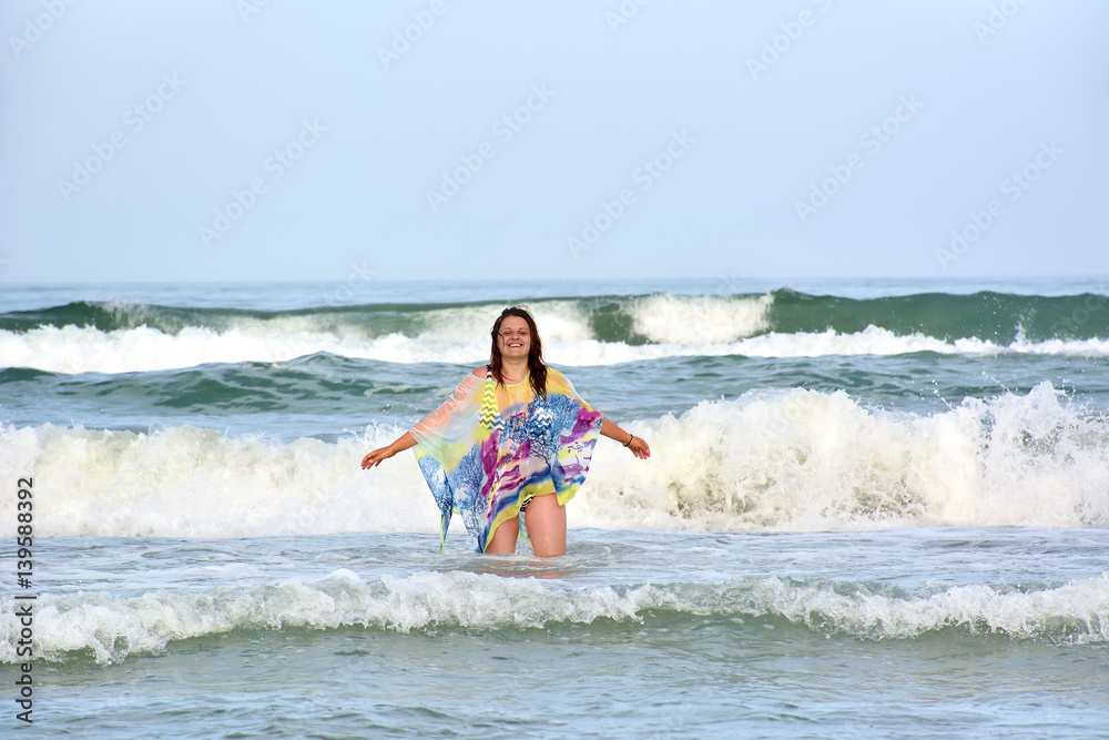 Young smiling woman standing in sea waves Young smiling woman standing in sea waves