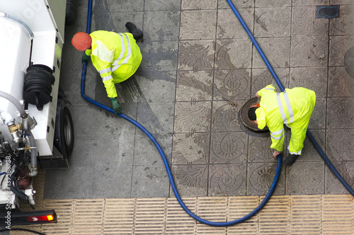 Ταπετσαρία sewer line drainage  by utilities workers with hose with pressurized water