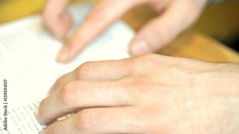 View of male's hands marking text while reading, close up, steadycam shot
View of male's hands marking text while reading, close up, steadycam shot