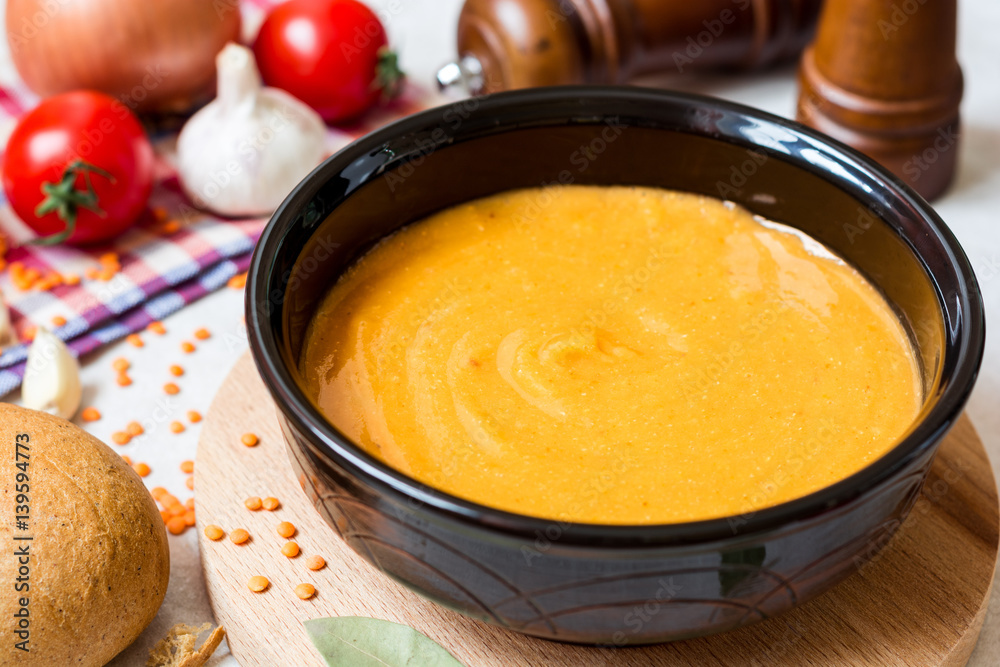 Red lentil cream soup in dark ceramic bowl Red lentil cream soup in dark ceramic bowl