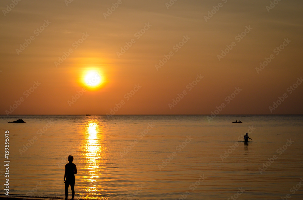 sunset at tropical beach with silhouettes