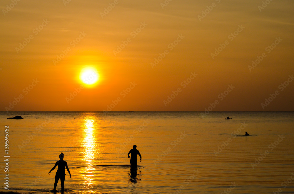 sunset at tropical beach with silhouettes