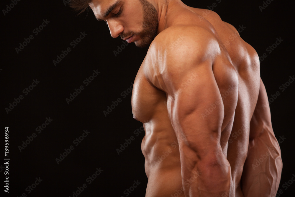 Strong Athletic Man - Fitness Model showing his perfect back isolated on black background with copyspace Strong Athletic Man - Fitness Model showing his perfect back isolated on black background with copyspace