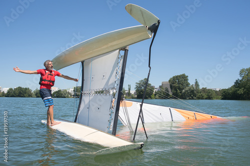 salior trying to right his catamaran after capsize photo