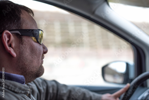 Young man driving the car in sunglasses
