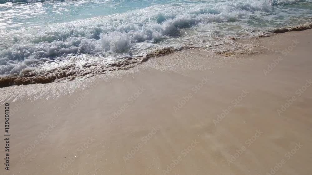 Surfing sea waves with foam on white sandy beach