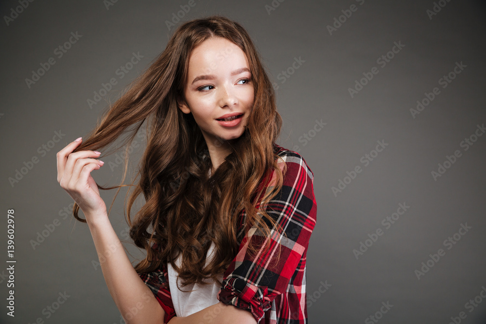 Smiling lovely young woman touching her hair and looking away Smiling lovely young woman touching her hair and looking away