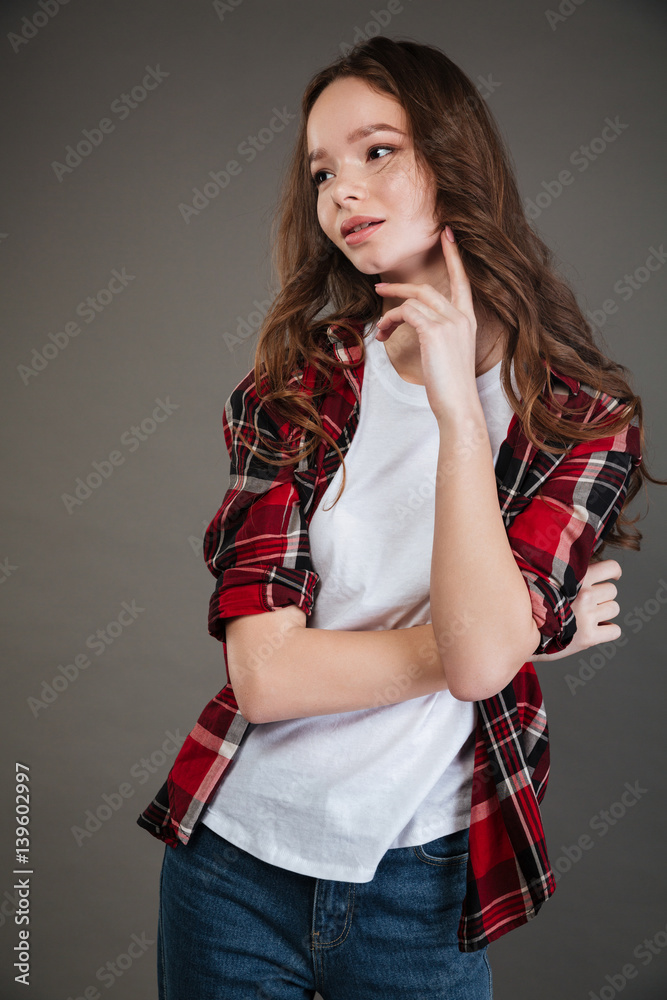 Pensive young woman in plaid shirt thinking and looking away