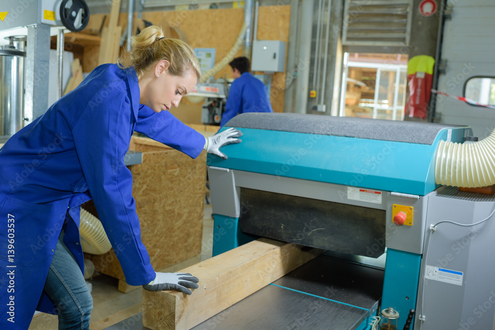 Worker feeding wood into machine Worker feeding wood into machine