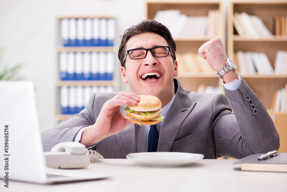 Fototapeta premium Hungry funny businessman eating junk food sandwich