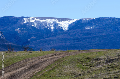 In the foreground is a dirt road leading to the snow-covered mountain tops.