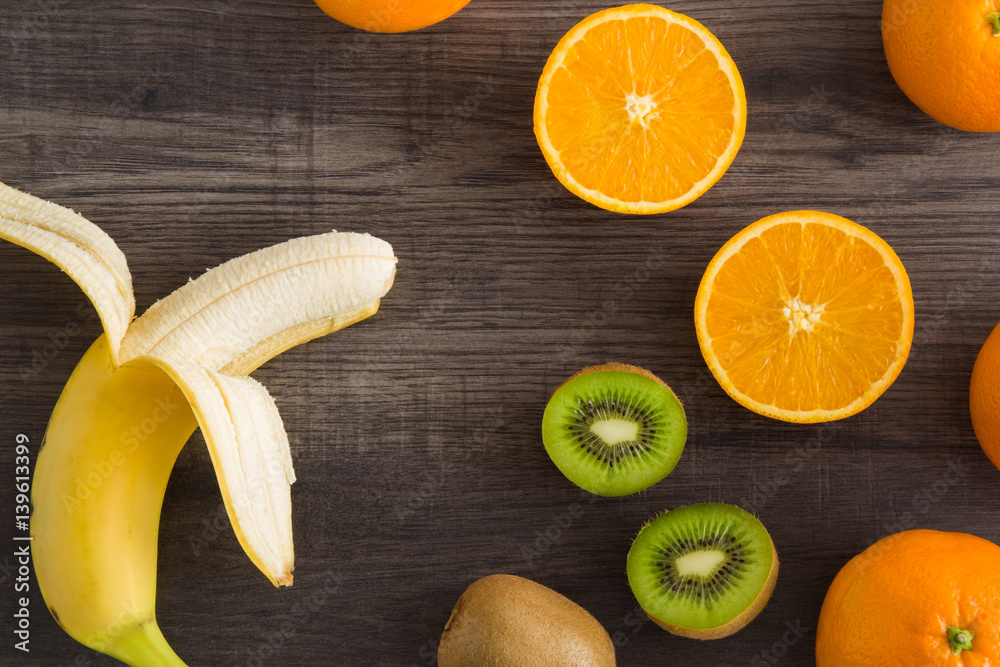 Banana with kiwi and orange on the wooden table in the kitchen. Healthy eating and lifestyle. Banana with kiwi and orange on the wooden table in the kitchen. Healthy eating and lifestyle.