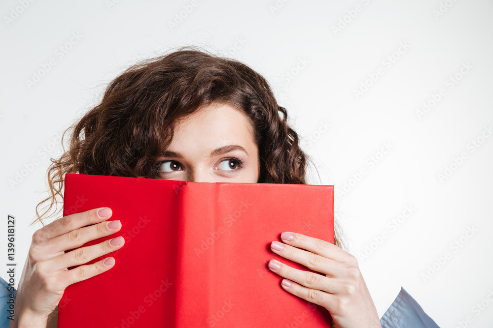 Portrait of a young woman covering her mouth with book Portrait of a young woman covering her mouth with book
